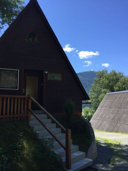 Eine Hütte mit einem Holzdach und Stufen, die zu ihr führen, umgeben von Natur.